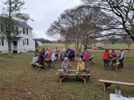 group of people making wreaths at picnic tables outdoors