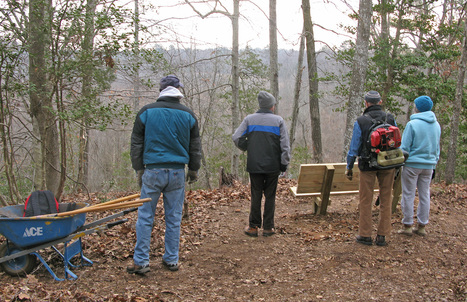 volunteers on a trail by a bench looking at view