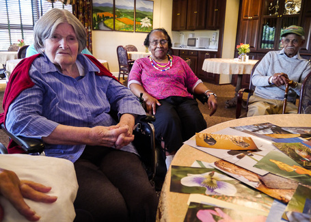 long-term care residents sitting around a table covered in nature photos