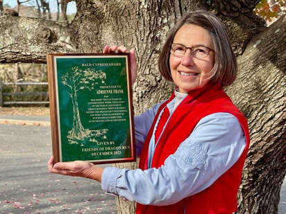 woman in red vest holding a plaque with an image of a tree