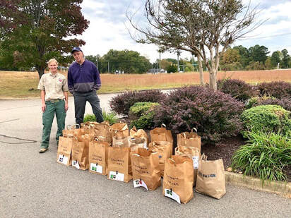 volunteer posed with forester and 19 shopping bags of acorns