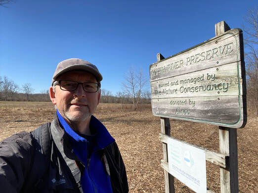 selfie of man by sign reading South River Preserve, owned and managed by the Nature Conservancy, donated by Alcoa
