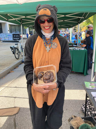 volunteer wearing a bear costume and holding a container of bear scat