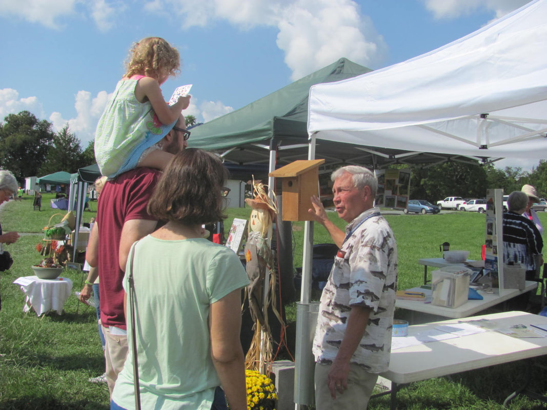 volunteer showing a bluebird box to a family at a festival