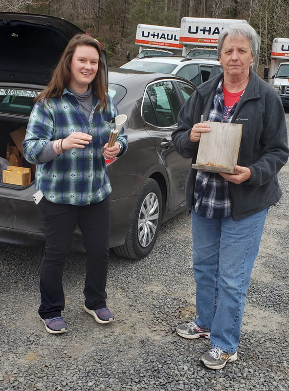 person giving another person a bee hotel in a parking lot