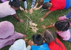 group of children gathered around a pile of nature objects like rocks and sticks