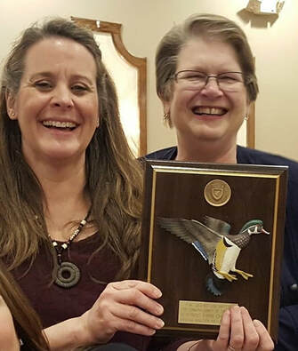 Two volunteers holding Ducks Unlimited award plaque
