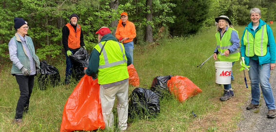 group of people picking up litter along a trail