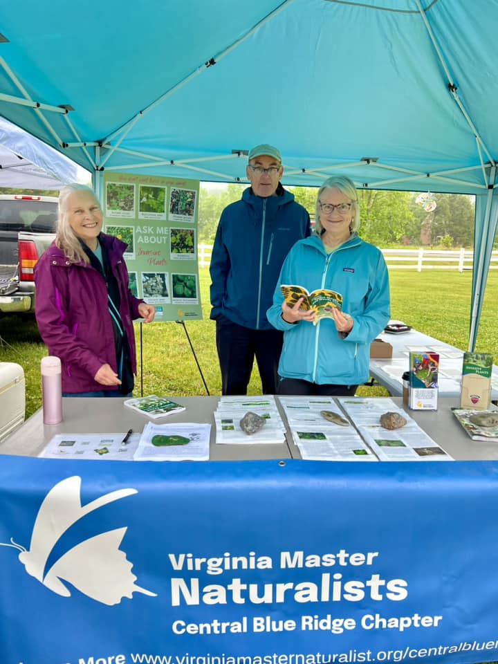 three volunteers at an outdoor outreach booth with a sign that says Virginia Master Naturalists Central Blue Ridge Chapter and displaying information about nature.
