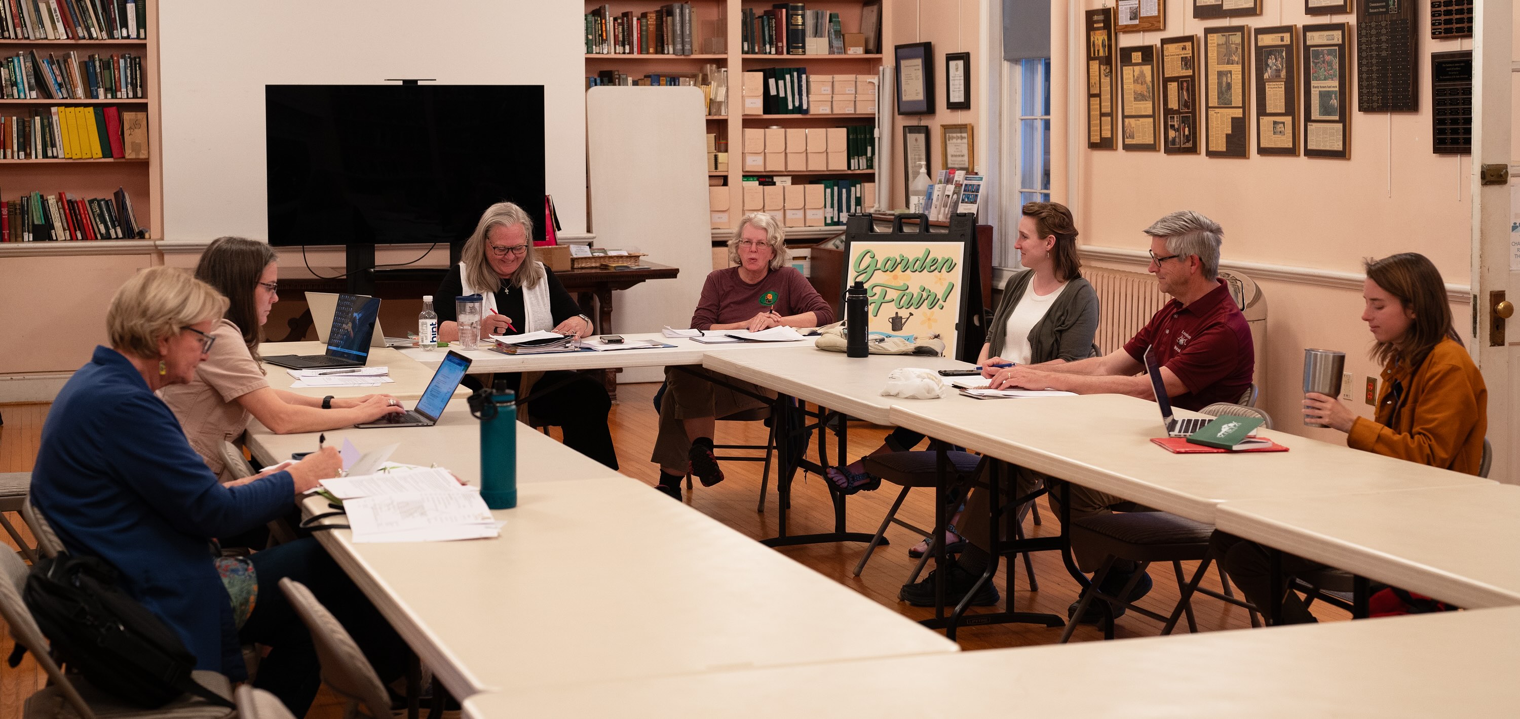 group of people seated around tables in a library