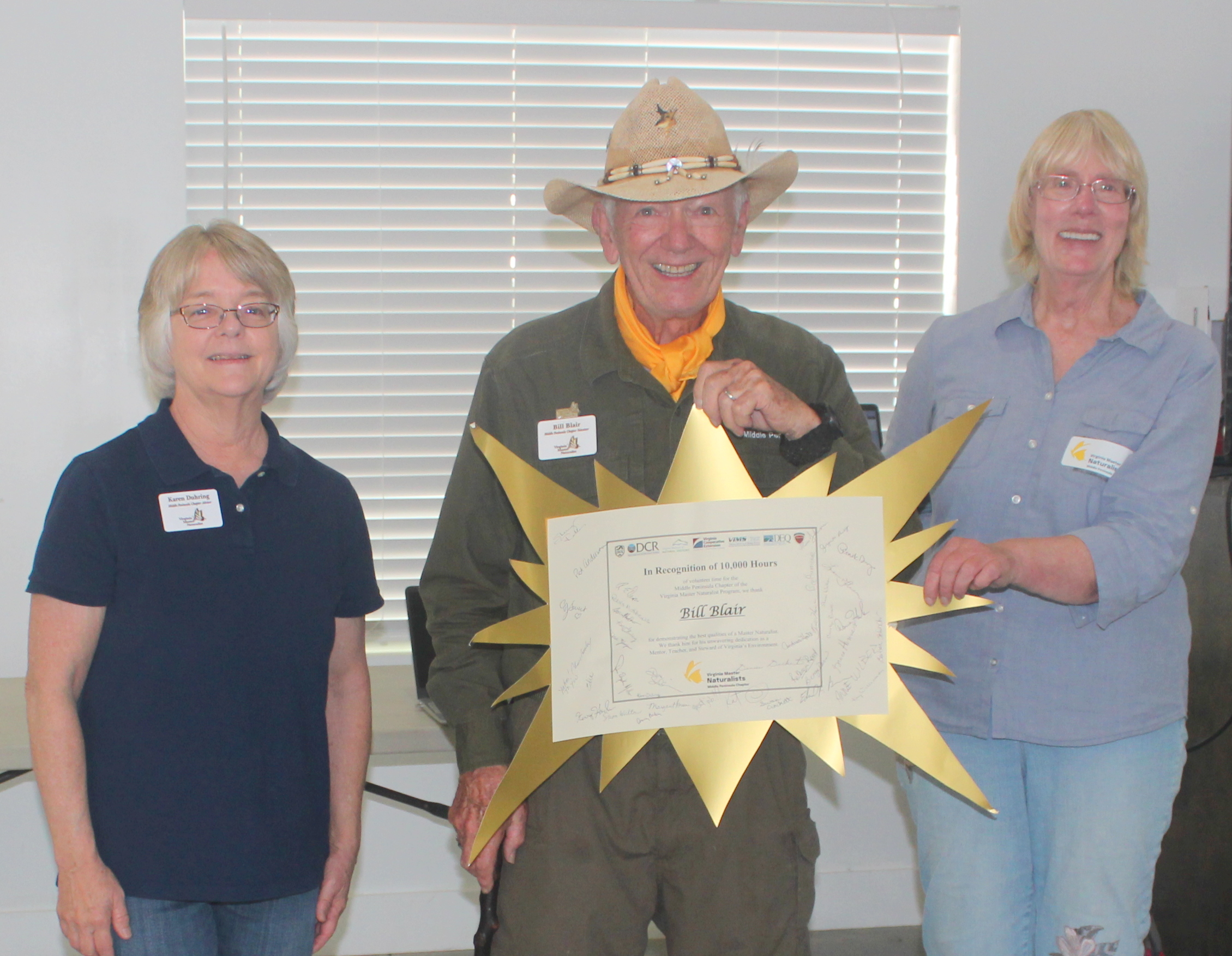 volunteer in a hat receiving signed certificate of recognition for 10,000 hours