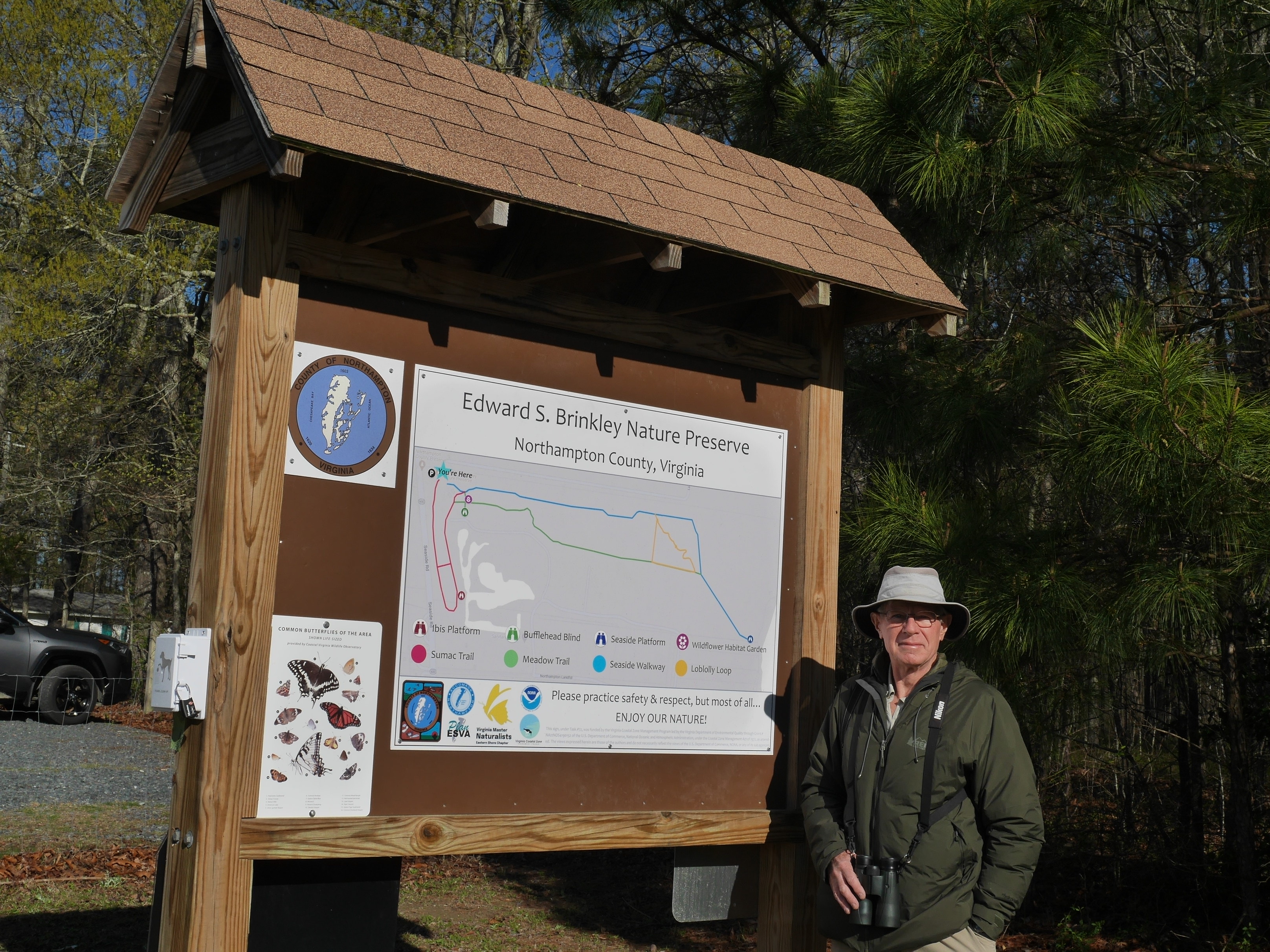 person standing by a trail kiosk