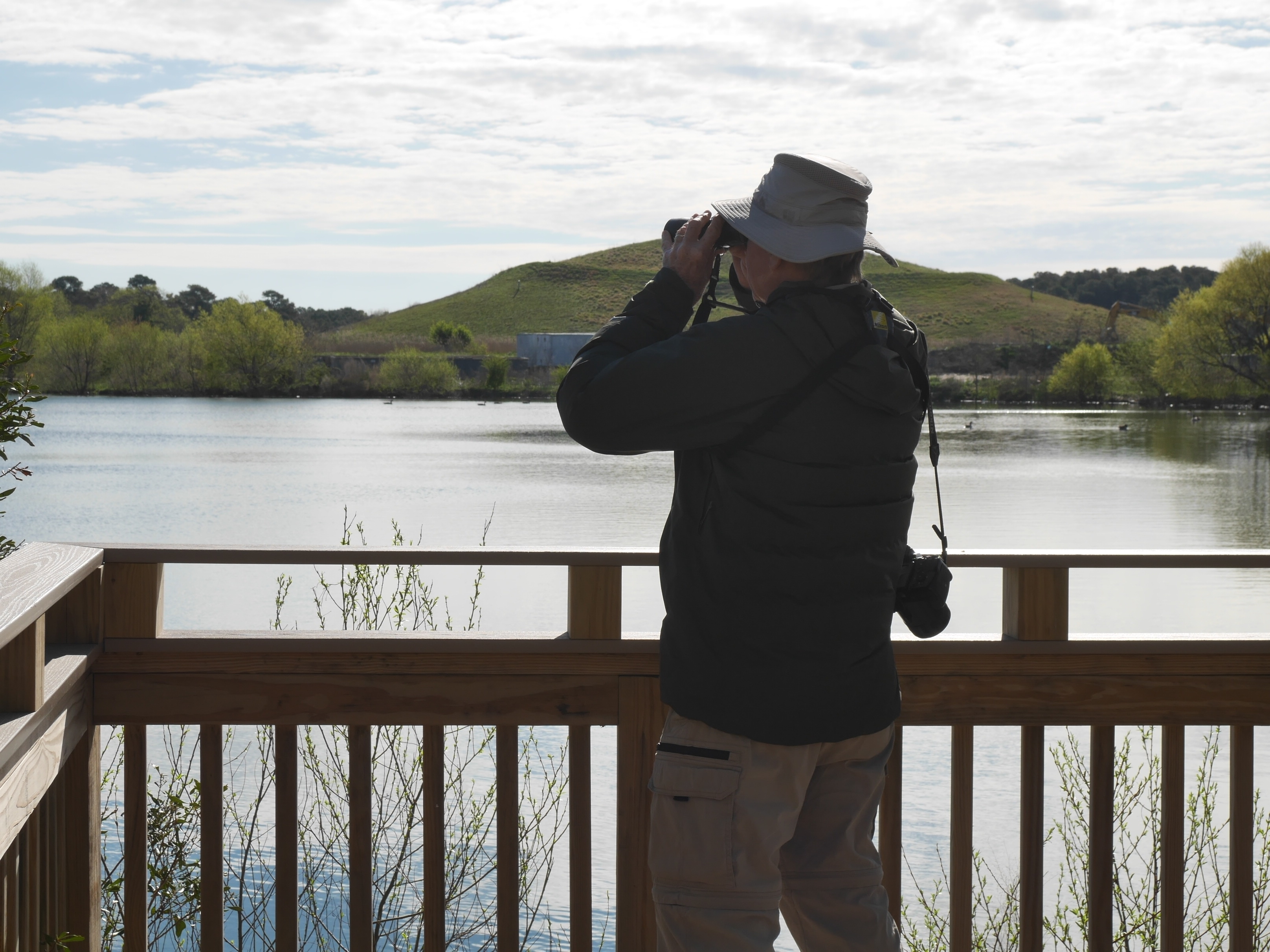 person looking out over the water with binoculars