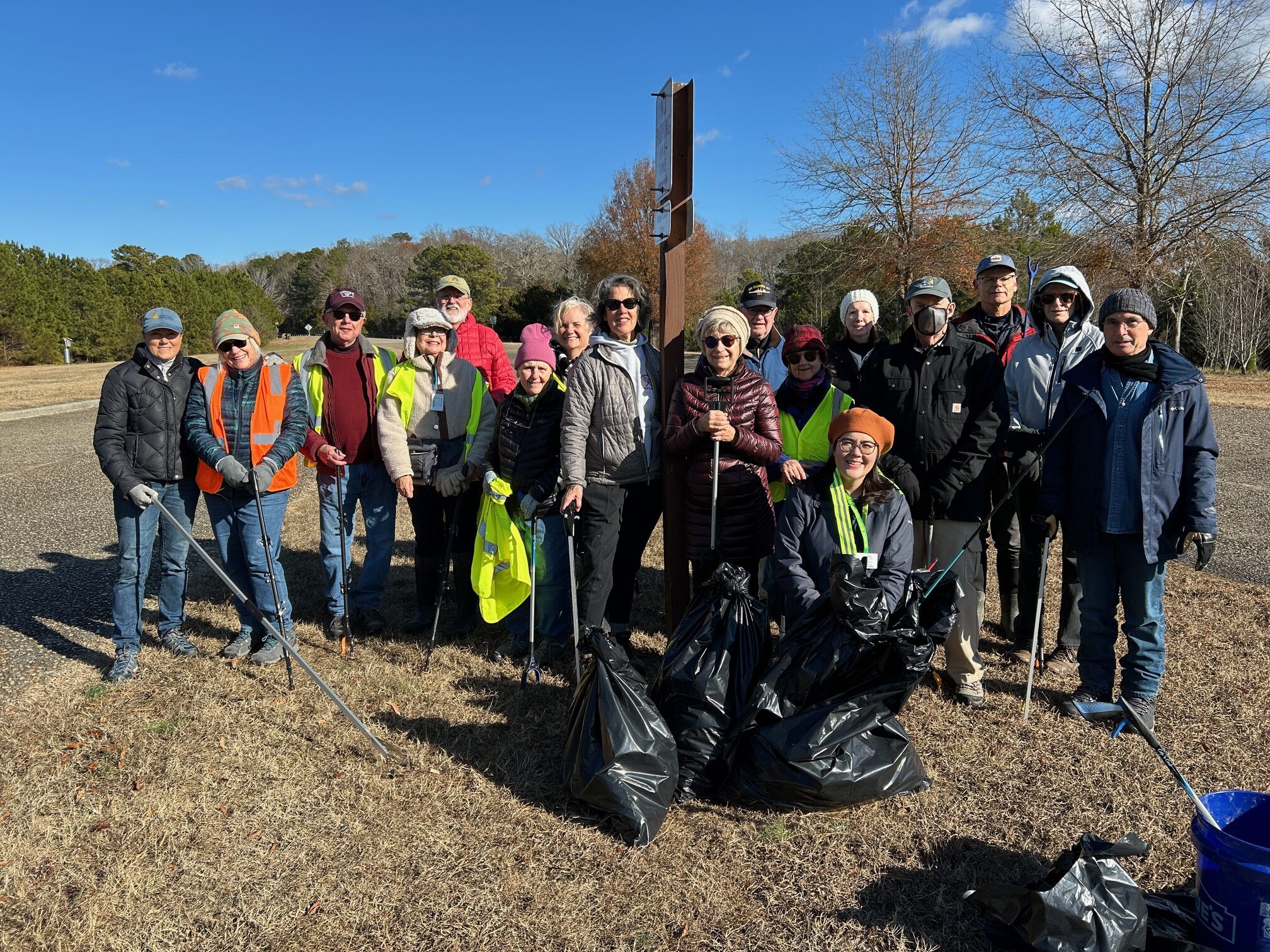 group of people posed with trash bags and trash pickers