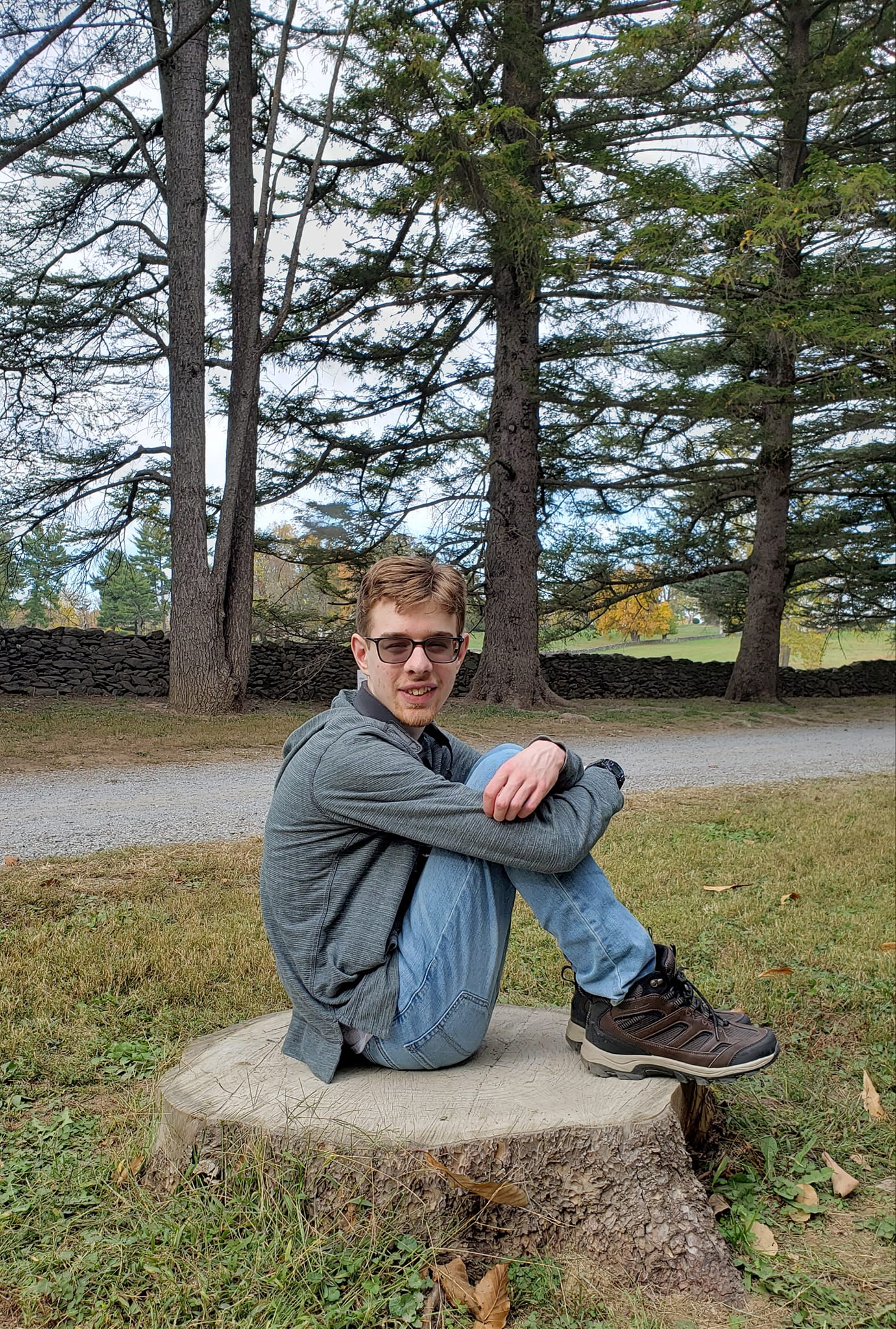 teenager sitting on a tree stump