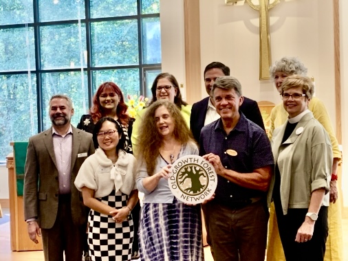 Group of nine people posed with a plaque that reads "Old Growth Forest Network"