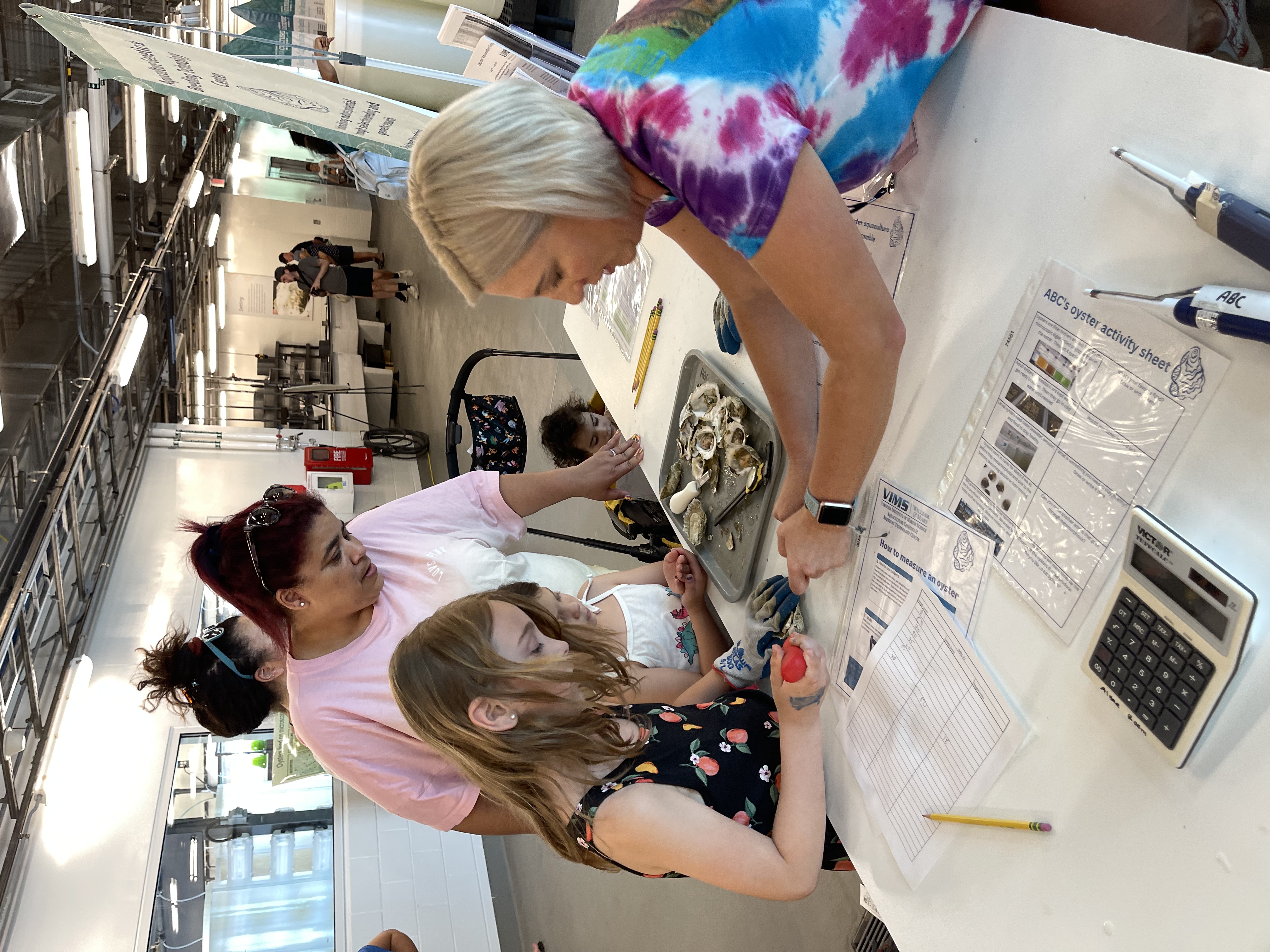 volunteer in a lab, showing a family some shells and marine organisms