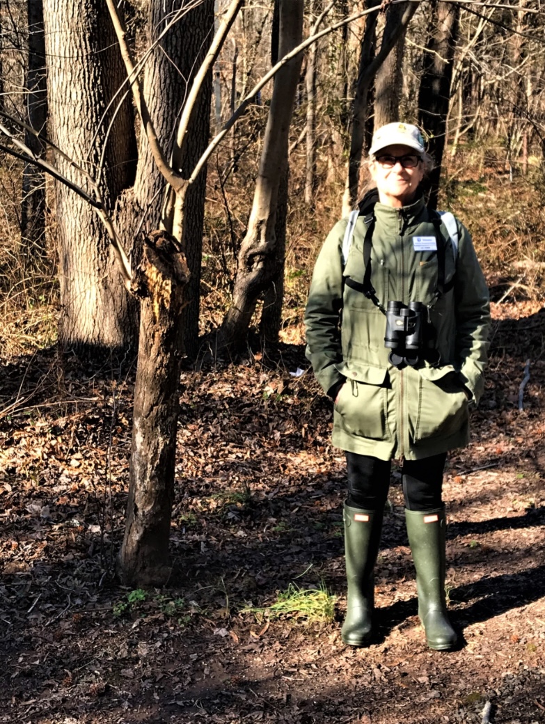 woman posed in rubber boots and binoculars outside in a forest