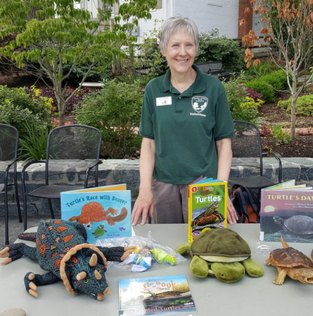 woman posed at a table with nature-related books and stuffed animals