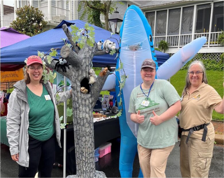 volunteers posed with a large model of a tree, and one person behind them in a shark costume