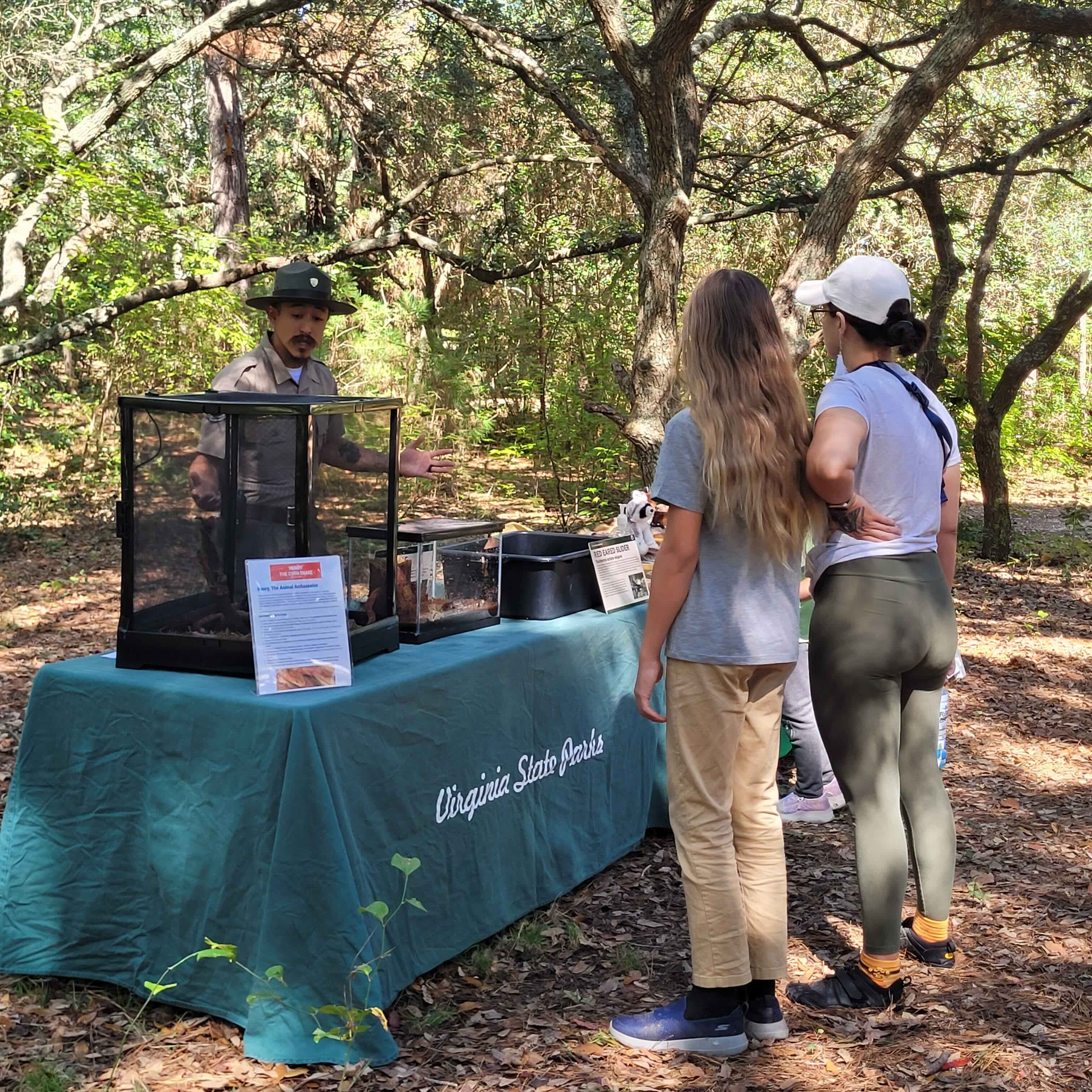adults and children talk to a park ranger at a Virginia State Parks table set up outdoors