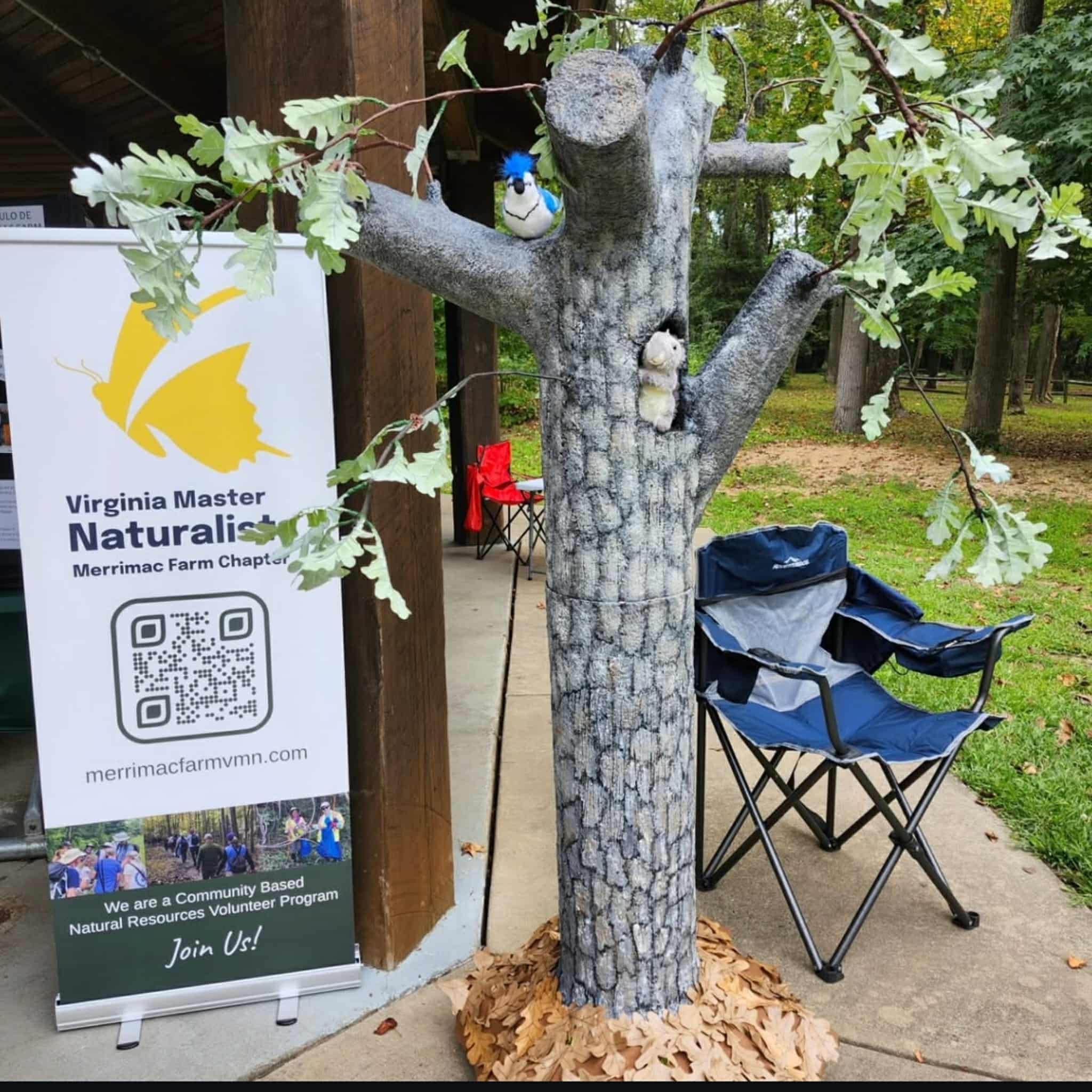 Open Popup for a model of a tree with stuffed birds and animals perched in it, next to a sign reading Virginia Master Naturalists Merrimac Farm Chapter