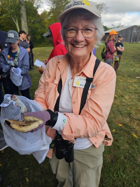 Smiling woman holds an animal in a mesh bag