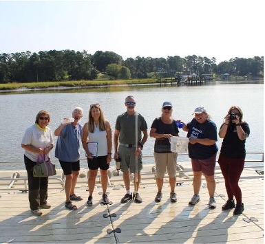 seven volunteers posed on a dock next to the water with water monitoring equipment