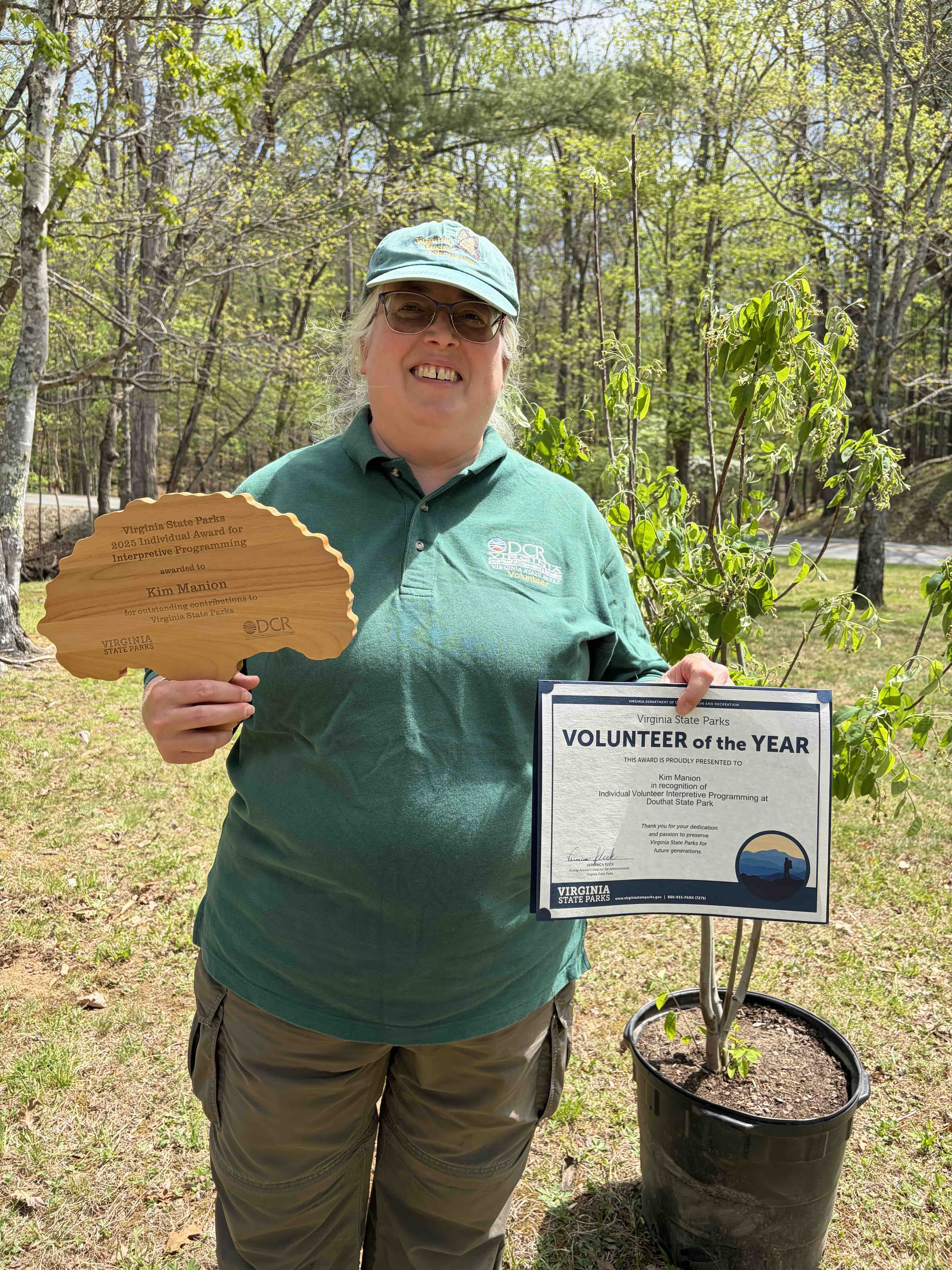 volunteer posing with certificate and plaque.