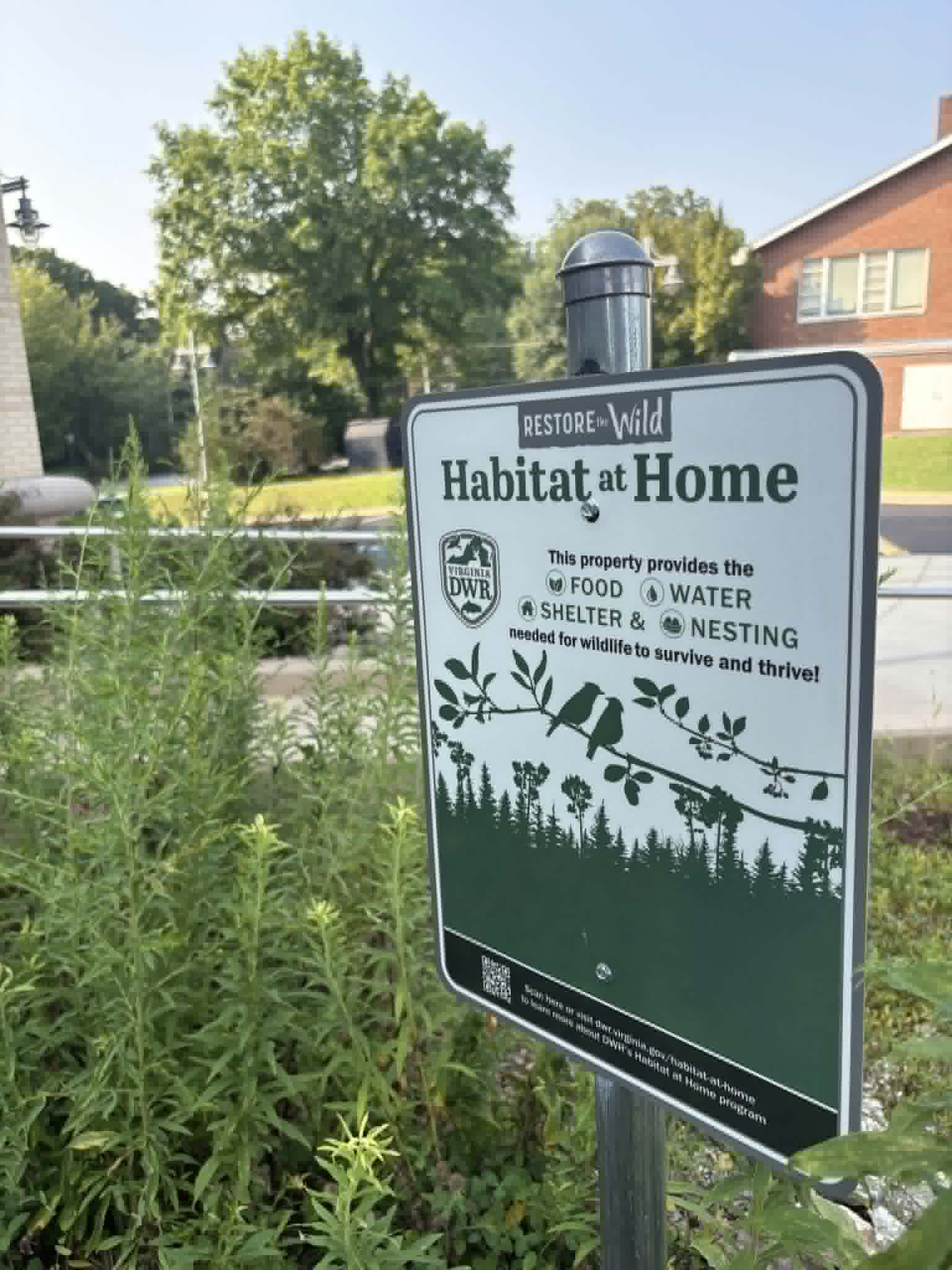 Sign in a garden reading Restore the Wild, Habitat at Home, this property provides the food, water, shelter, and nesting needed for wildlife to survive and thrive.