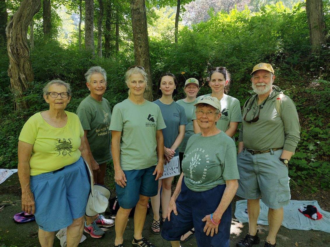 eight volunteers pose near a stream