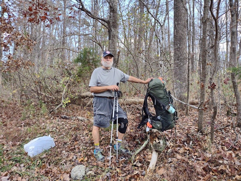 man with hiking poles and backpack in a forest