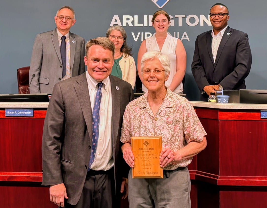 volunteer with award plaque posed with five county officials