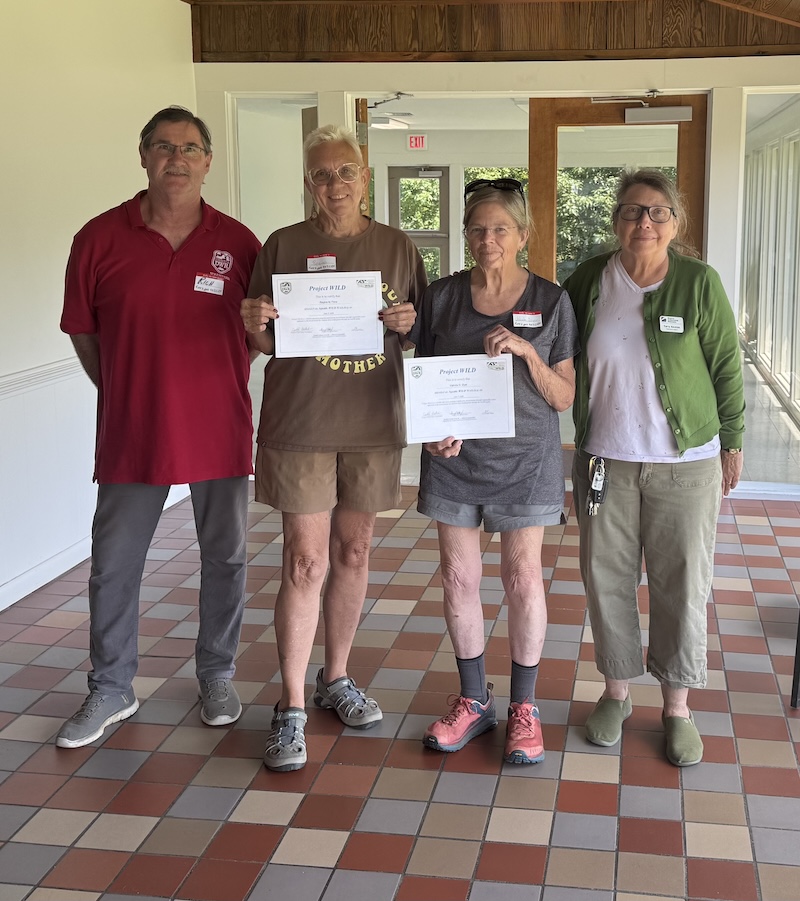 two volunteers pose with certificates and two other leaders